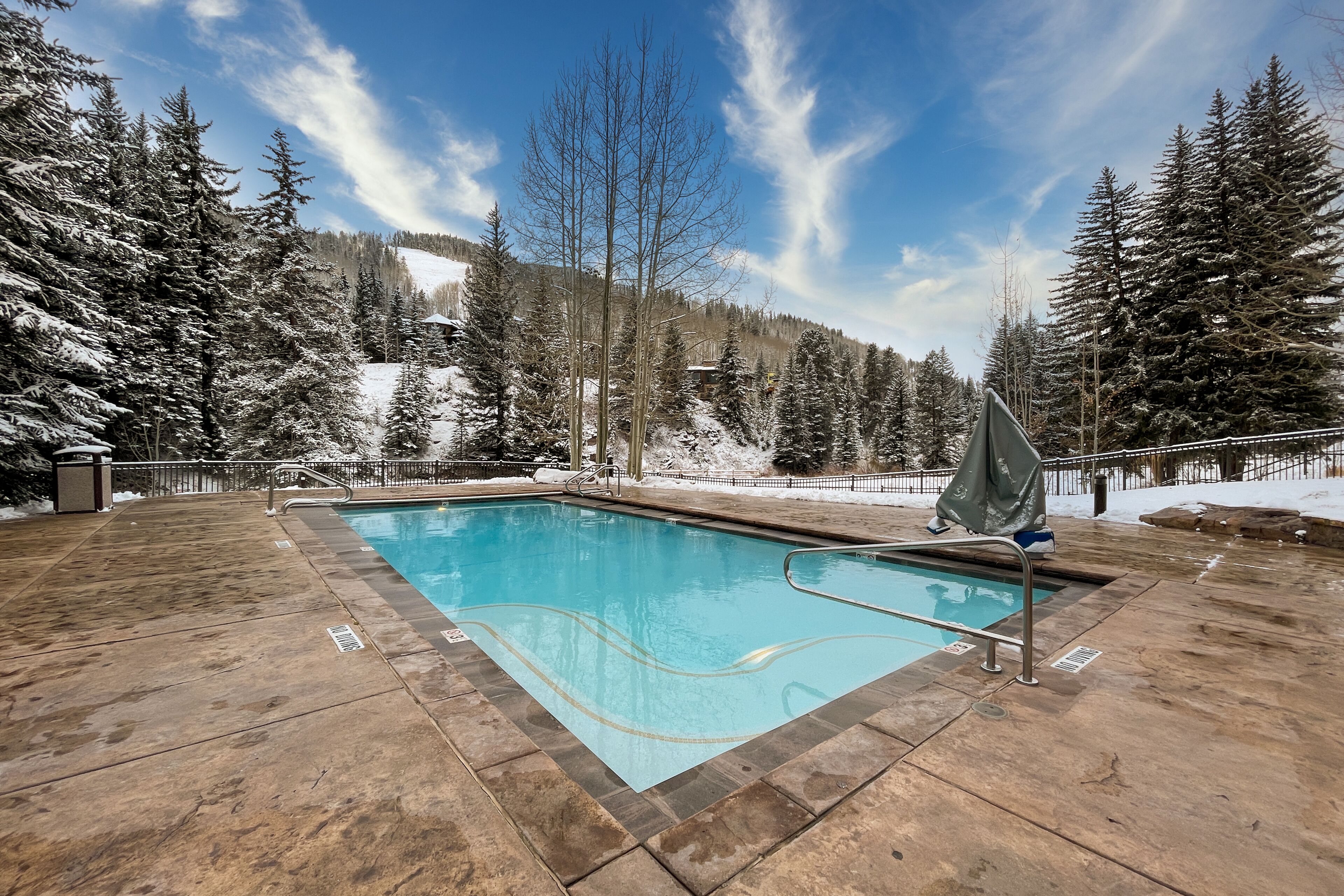 Una piscina rettangolare con linea d'acqua blu trasparente, circondata da un solarium in pietra.