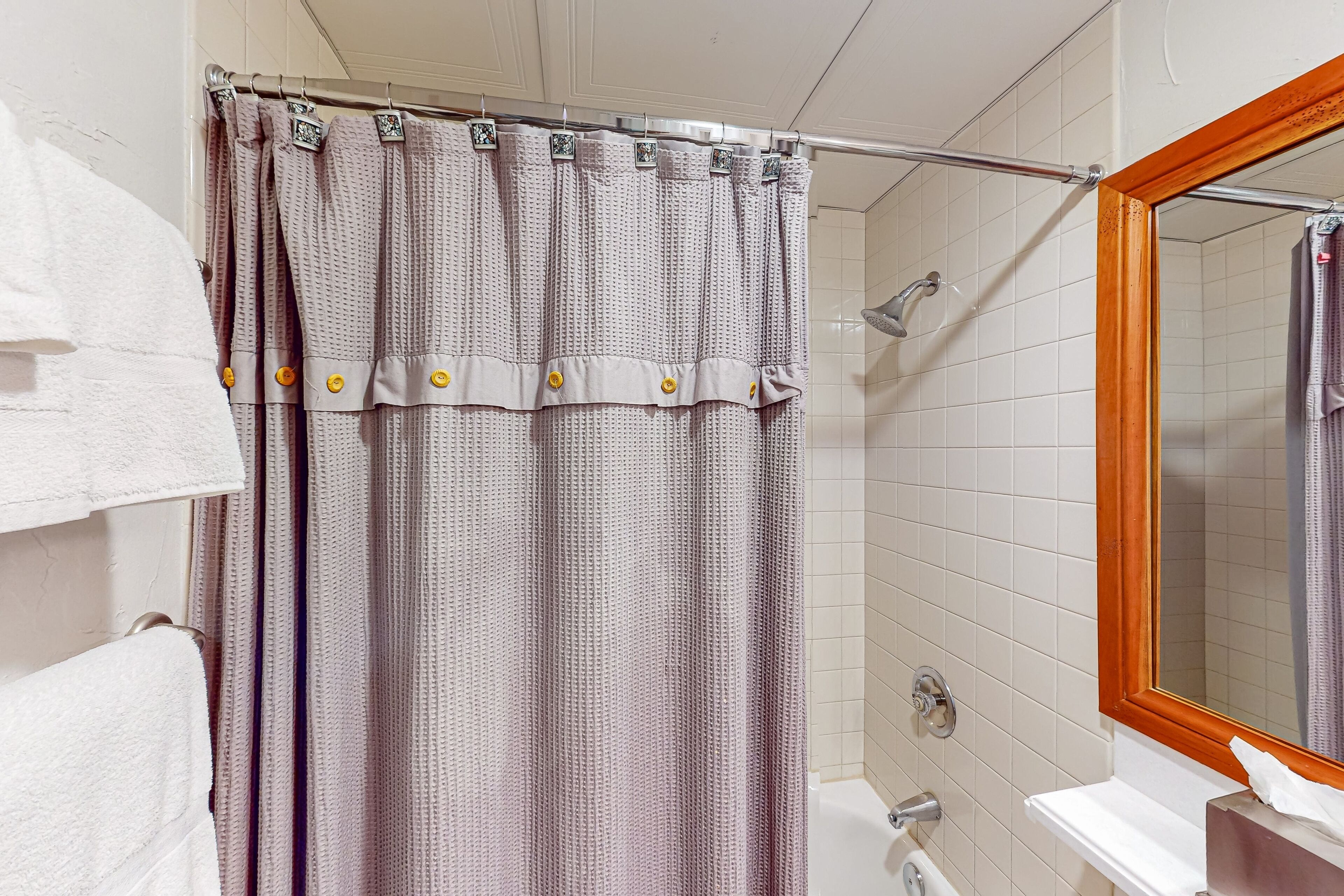 A bathroom with a shower curtain, a bathtub, and a mirror.