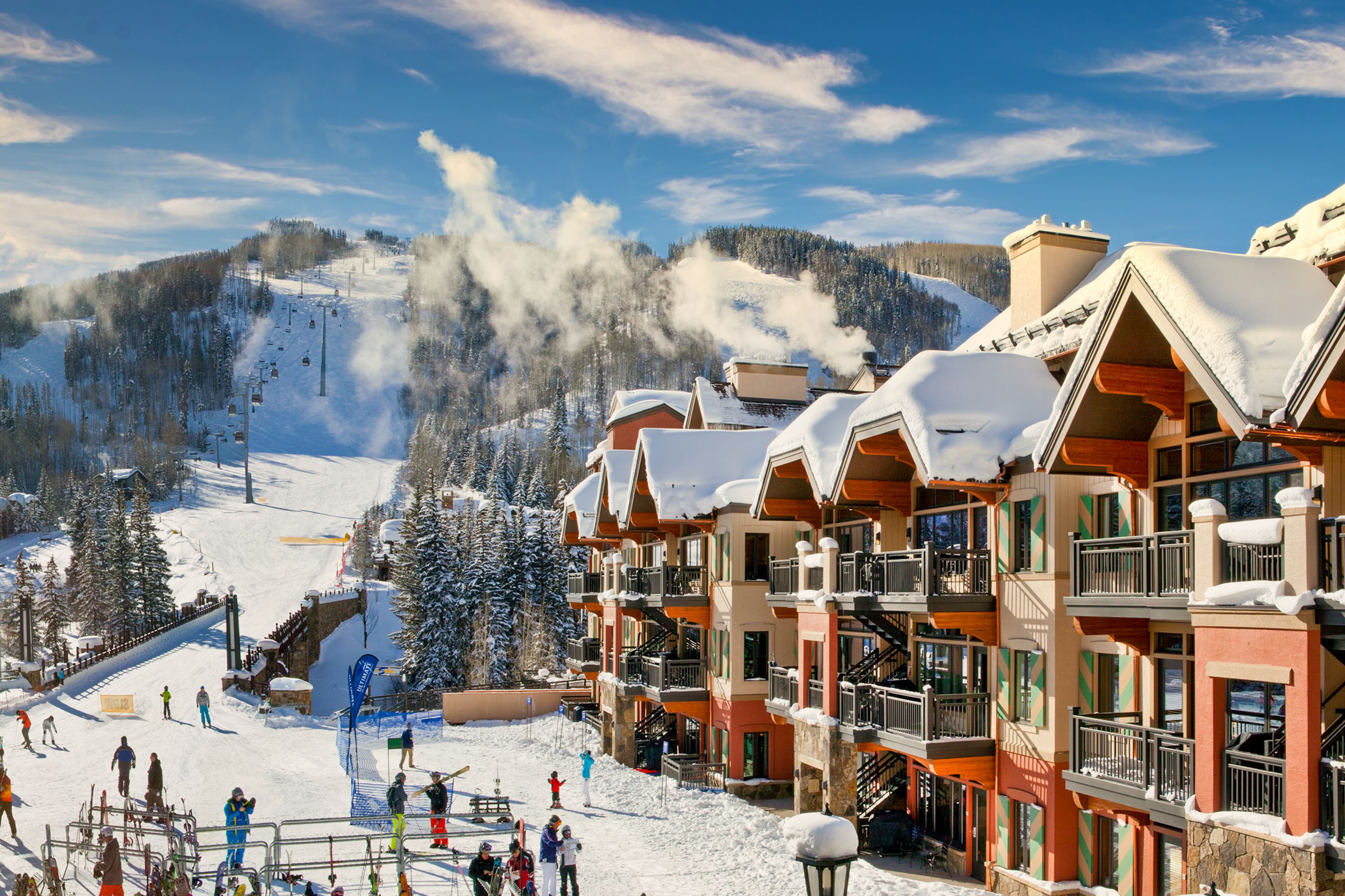 A ski resort with multi-story buildings, ski lifts, and a snowy mountain backdrop.