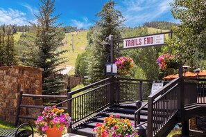 A 'Trails End' sign with a stone wall and flower pots in the foreground. - Lion Square Lodge (Vail)