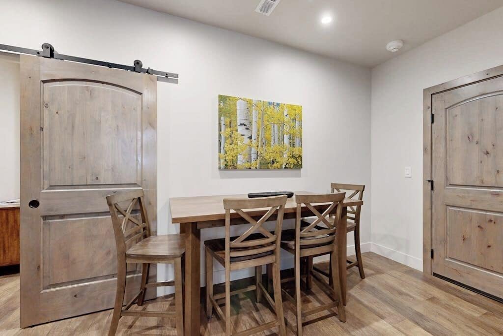 Un coin repas avec une table et des chaises en bois, une porte coulissante de style rustique et un tableau accroché au mur.