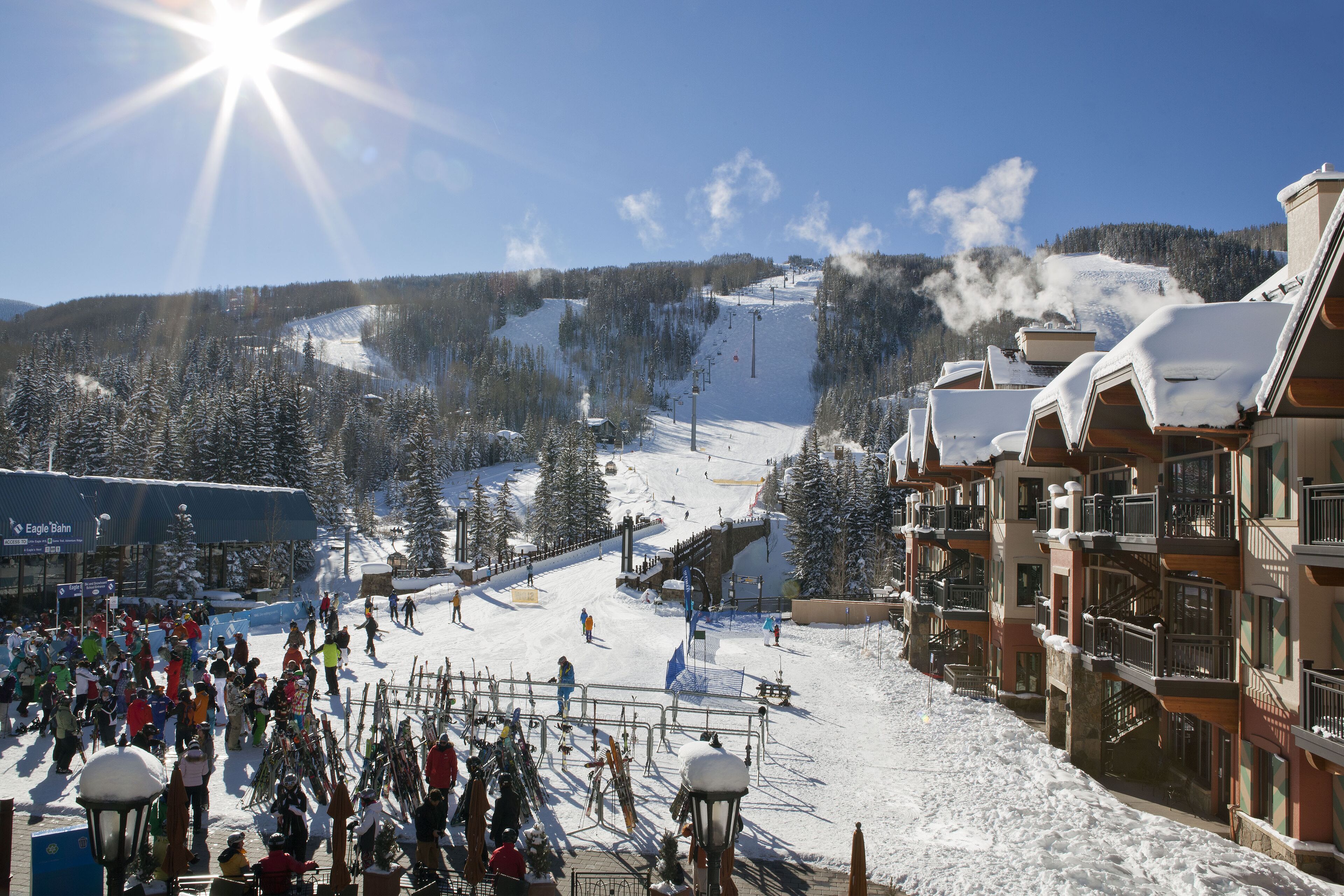 Ein Skigebiet mit Seilbahn, schneebedeckten Bäumen und Gebäuden mit Balkonen.