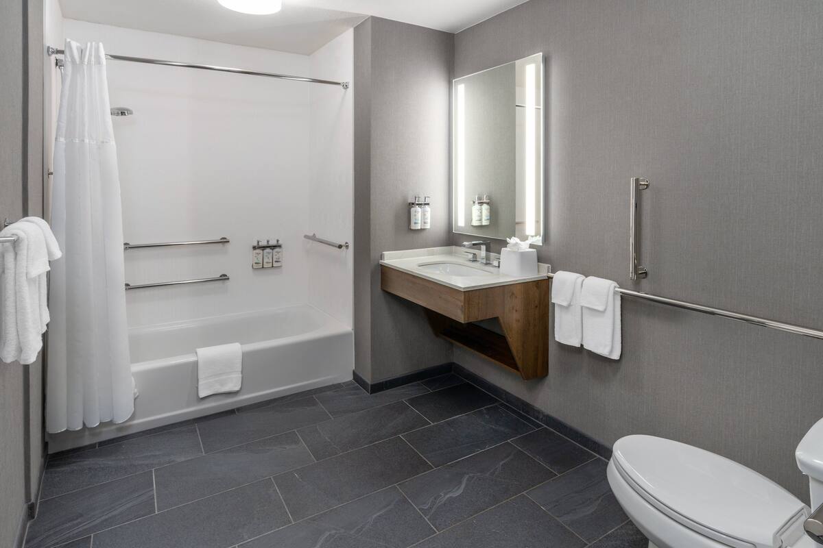 A modern bathroom with a bathtub, a sink, a toilet, and a mirror.