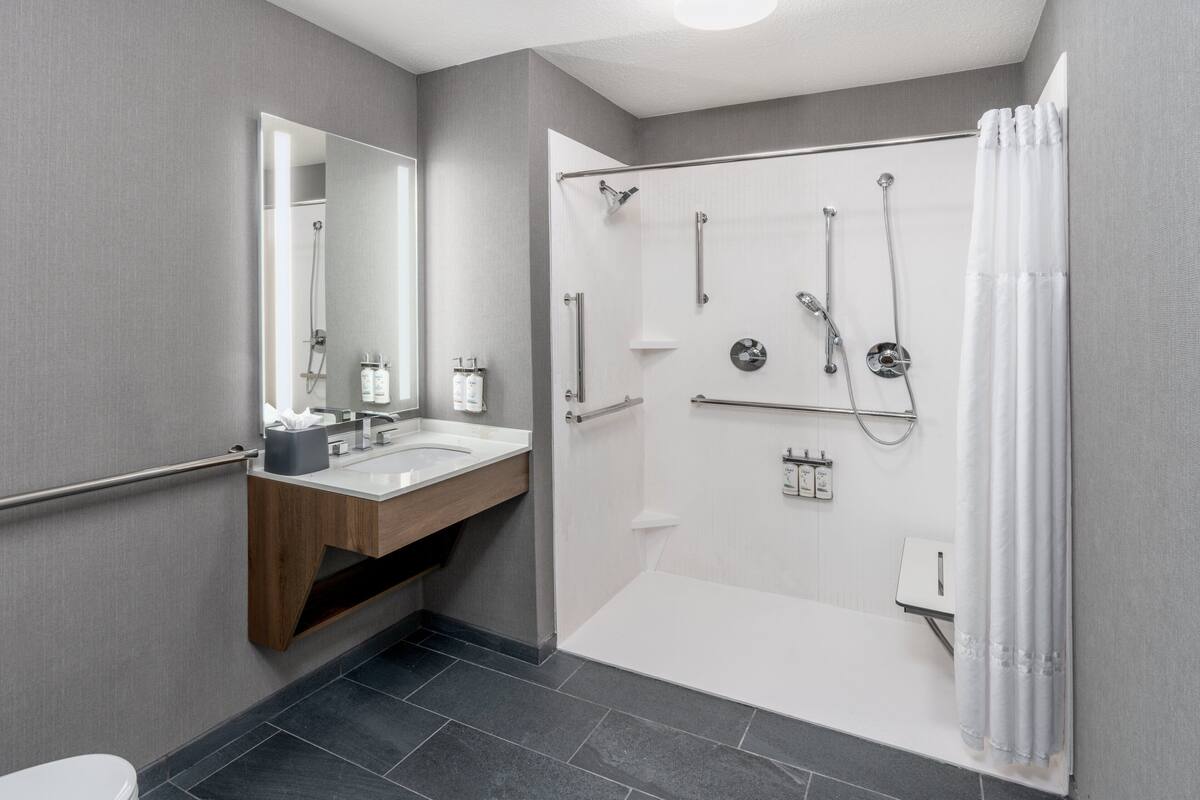 A modern bathroom with a shower, toilet, and sink.