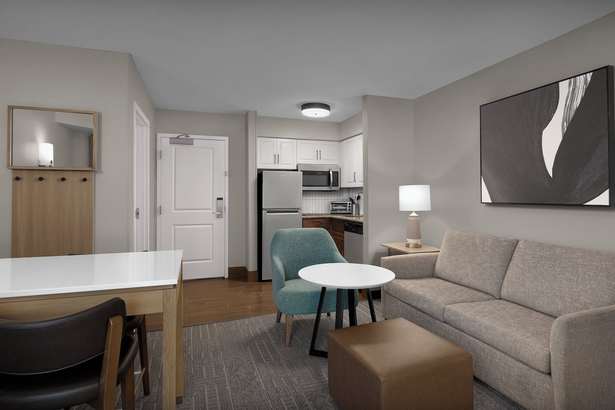 A compact living space with a kitchenette, a dining area, and a seating area with a sofa and a small table.