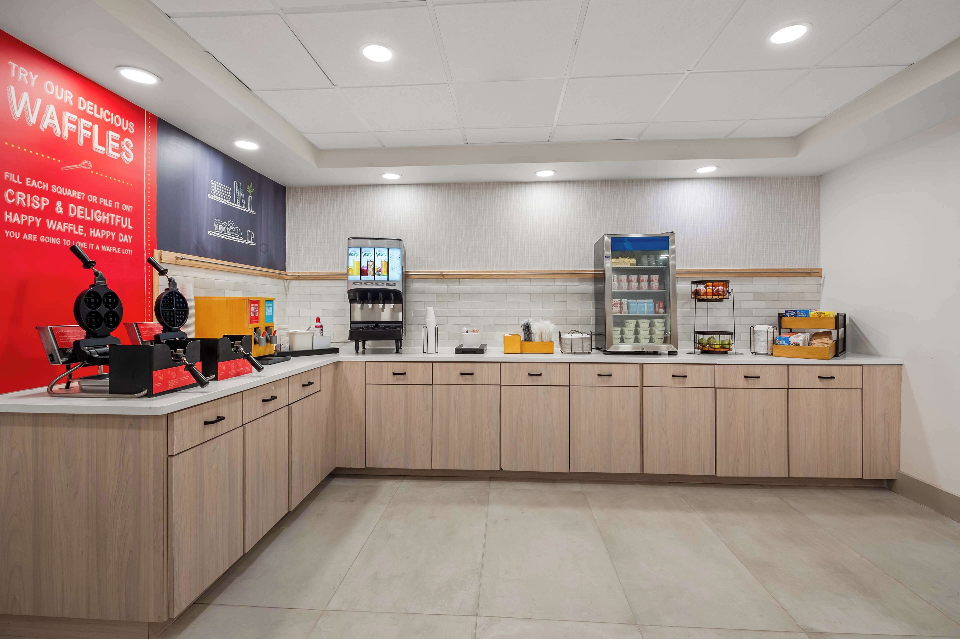 A kitchen area with waffle-making equipment, a coffee machine, and a beverage dispenser.