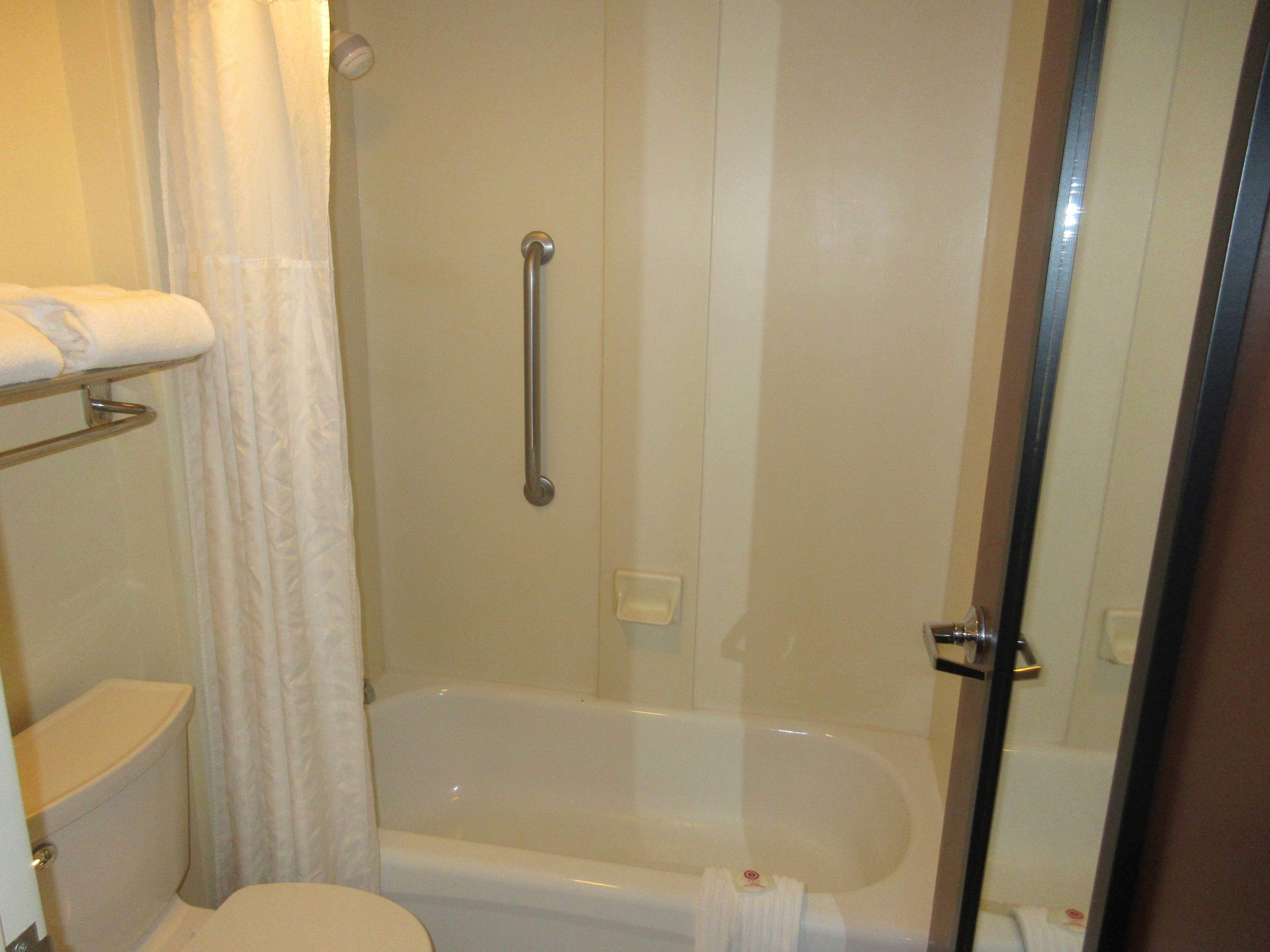 Een badkamer met een bad, toilet en douche.
