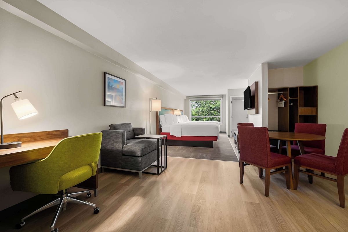 Una habitación de hotel con cama, escritorio, sillas y televisor.
