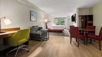 Ein Hotelzimmer mit Bett, Schreibtisch, Stühlen und einem Fernseher.