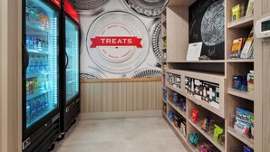 Una sección de aperitivos y dulces con vitrinas refrigeradas y estantes llenos de diversos bocadillos y bebidas.