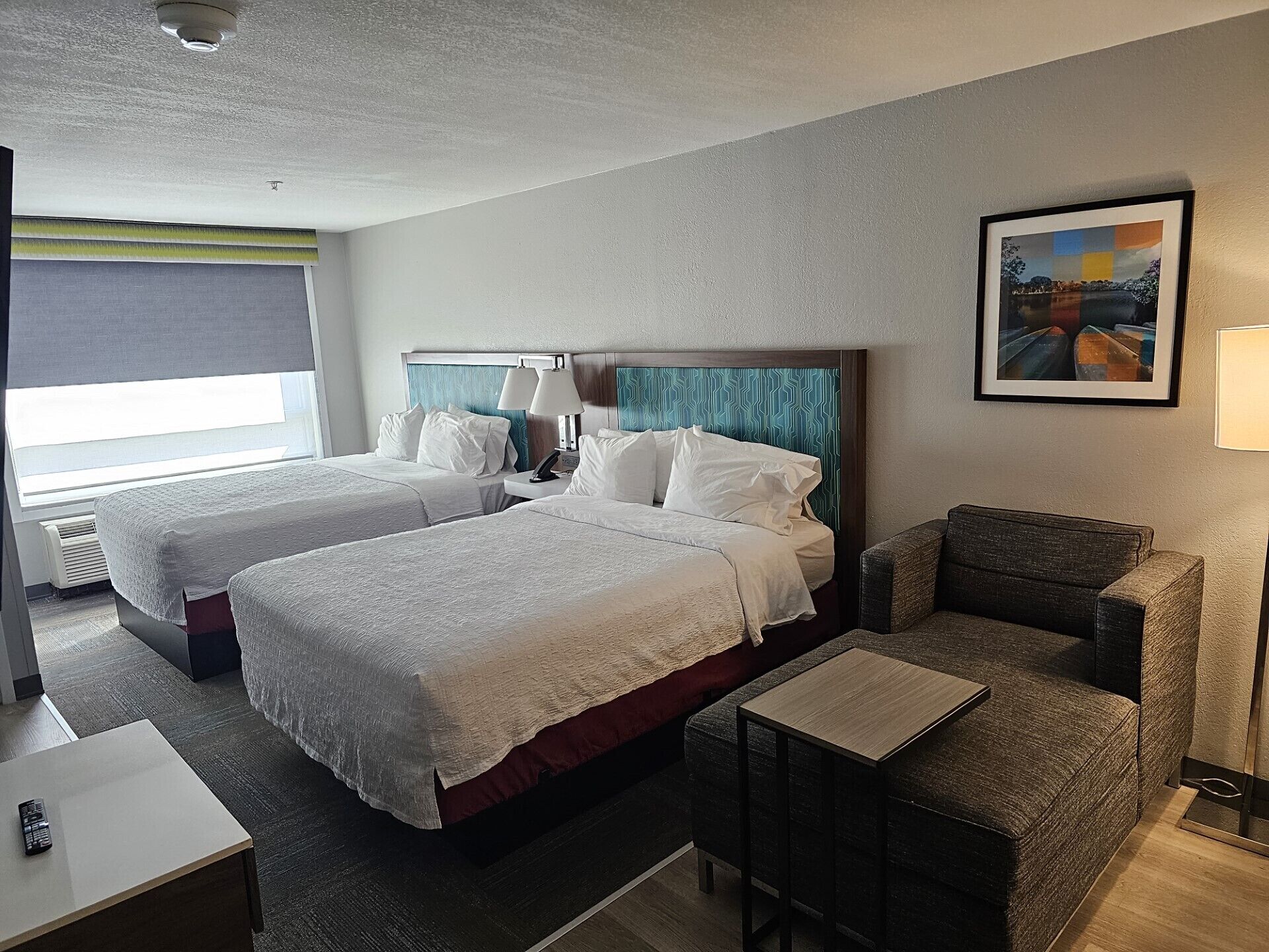 A hotel room with two beds, a sofa, a small table, and a painting on the wall.