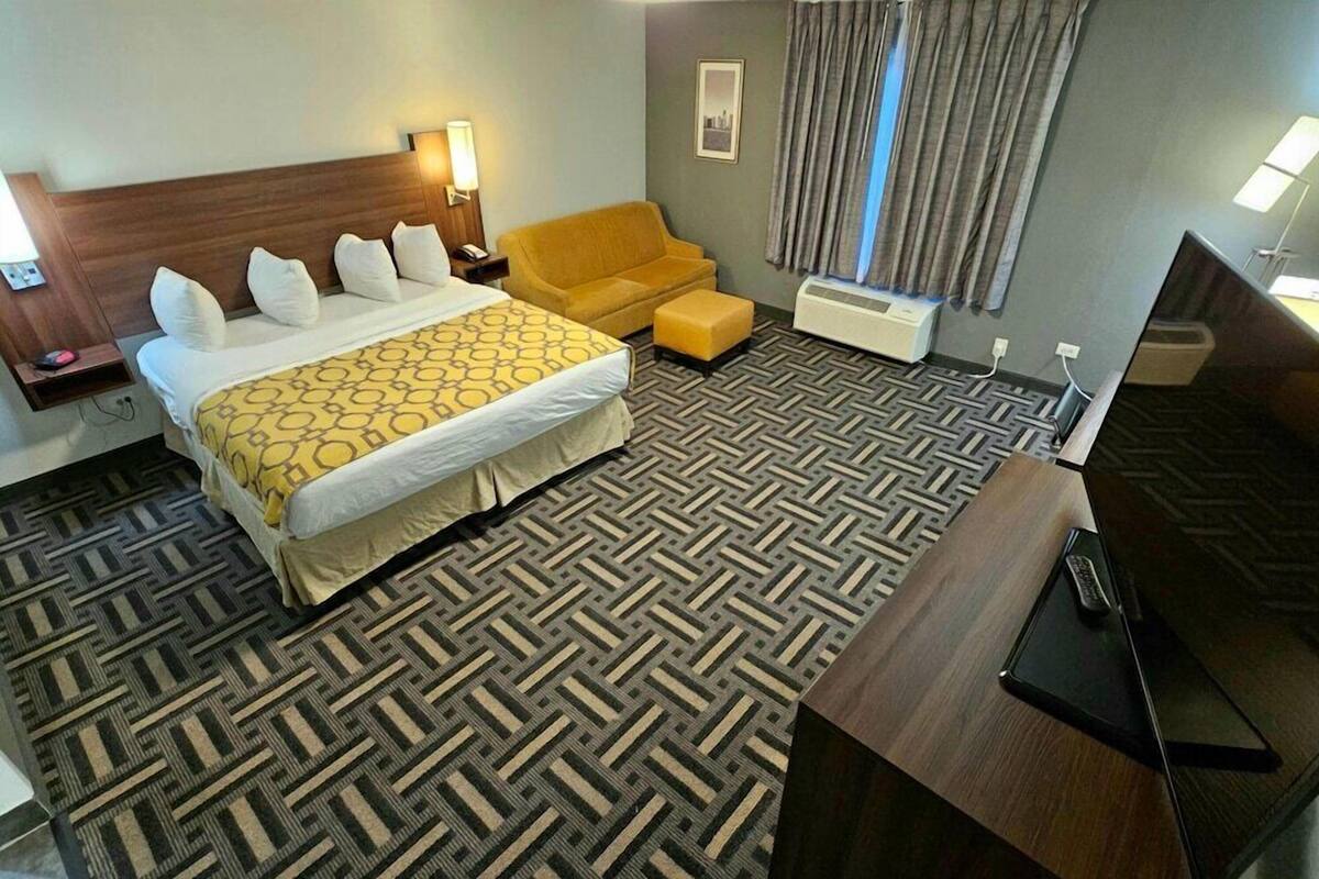 Una habitación de hotel con cama, sofá, escritorio y televisor.