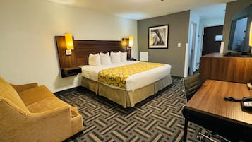 A hotel room with a large bed, a sofa, a desk, and a television.