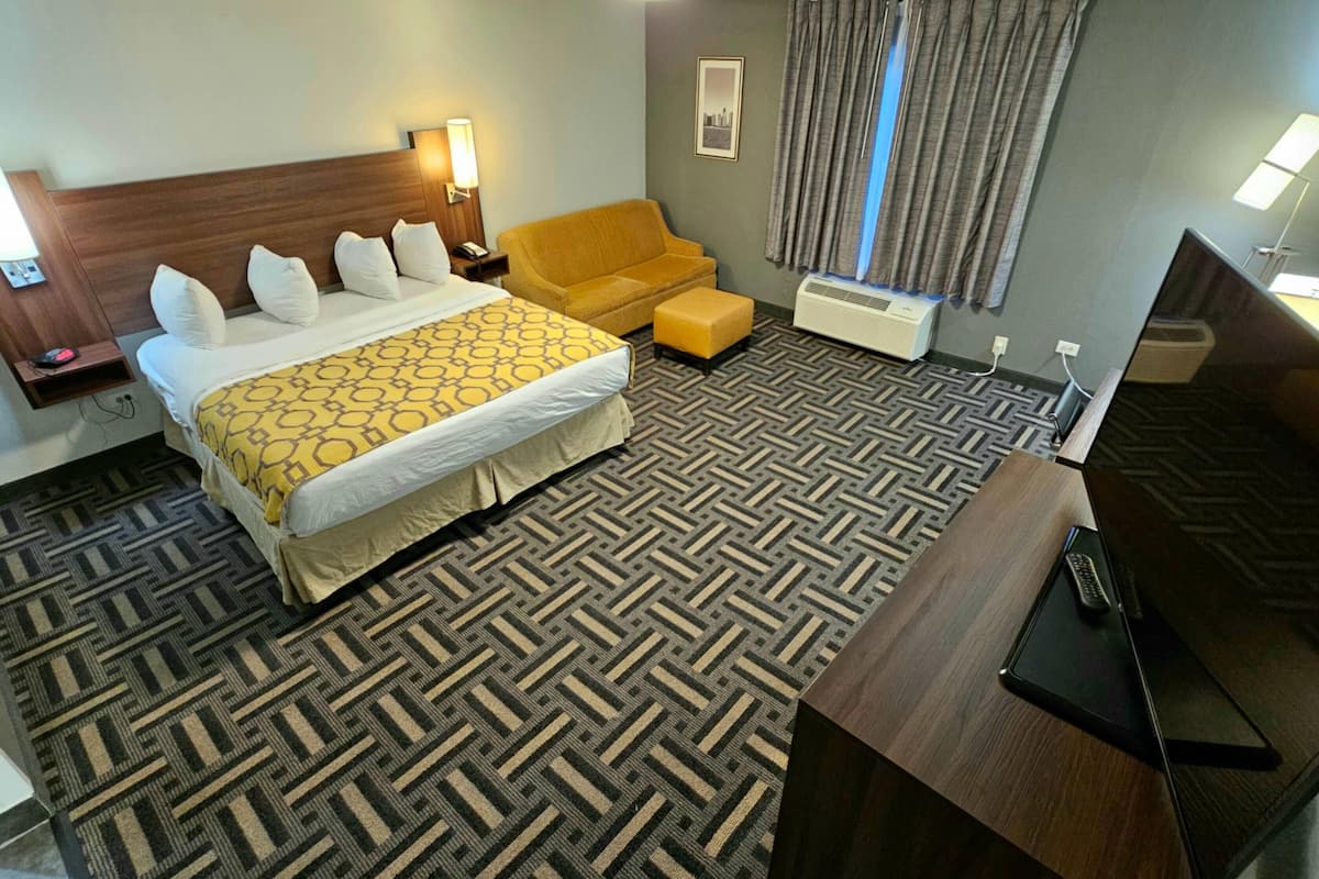 Een hotelkamer met een groot bed, een bank, een bureau met een laptop en een televisie.