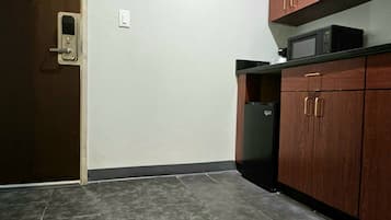 A small kitchen with dark tiles, wooden cabinets, and a microwave.