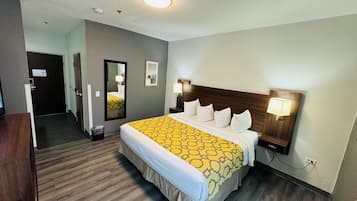A hotel room with a large bed, two bedside lamps, a mirror, and a wooden headboard.