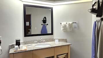 A bathroom with a granite countertop sink, a mirror, a towel rack, and a shower curtain.