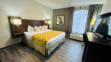 Una habitación de hotel con una cama grande, dos lámparas de noche, un televisor y una ventana con cortinas.