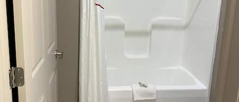 A bathroom with a shower, toilet, and a door.