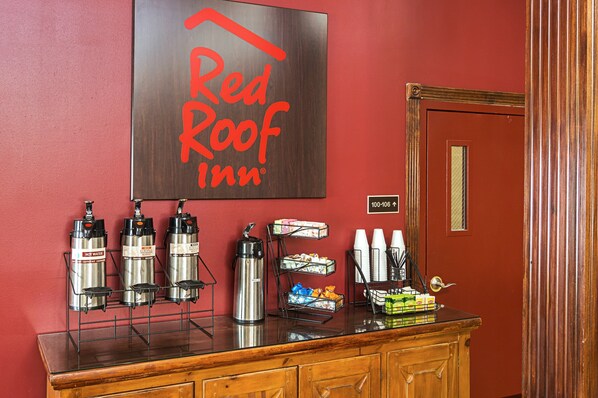 A Red Roof Inn reception area with a coffee station, hot water dispensers, and a sign indicating room availability. - Red Roof Inn & Suites Lake Orion/ Auburn Hills (Lake Orion)