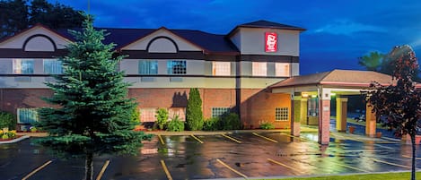 A hotel with a parking lot and a covered entrance.