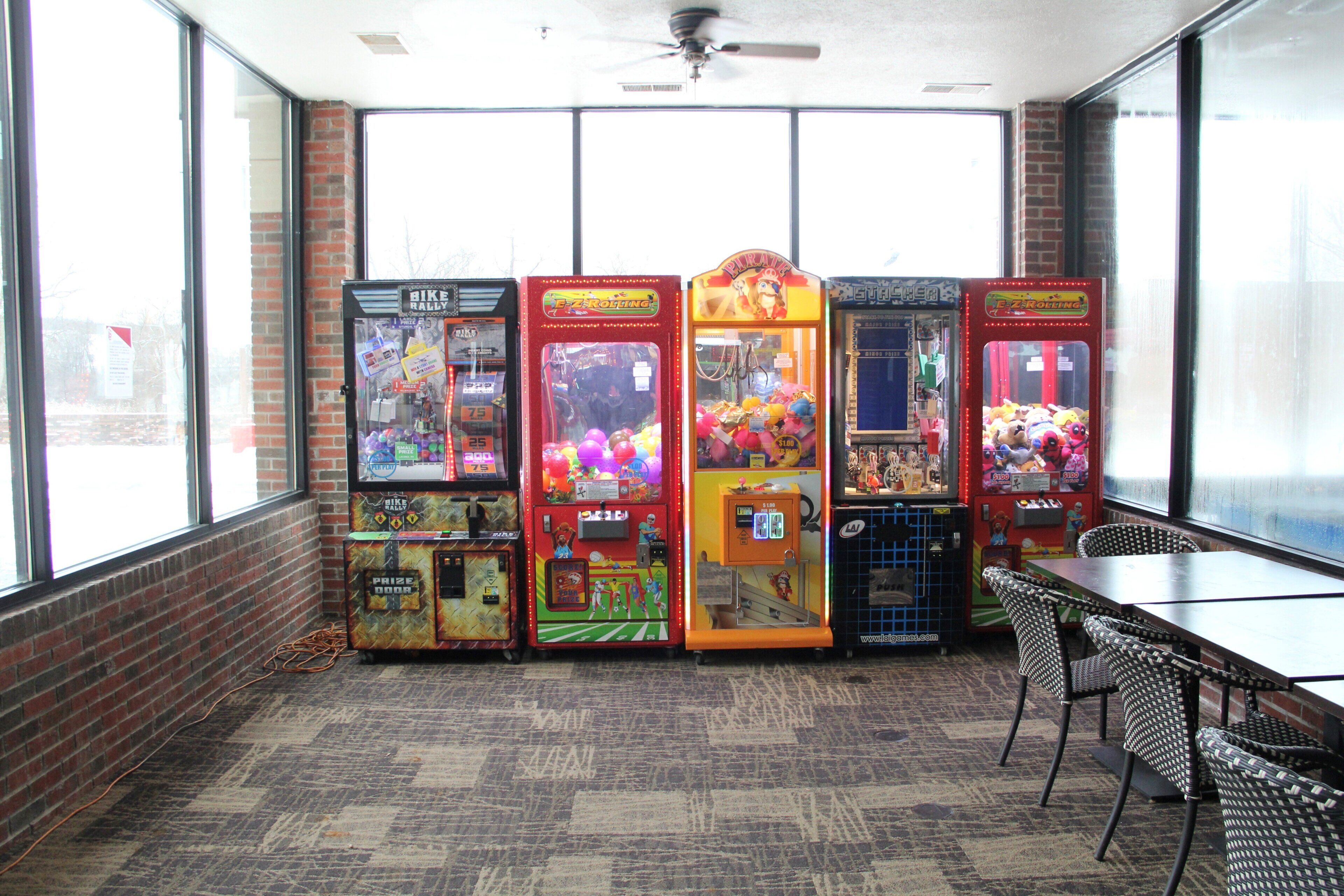 A room with four arcade machines, a table, and chairs.