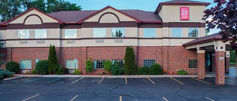 A Red Roof Inn & Suites with a brick facade, multiple windows, and a parking lot.