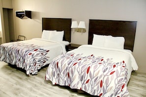 Habitación de hotel con dos camas, cada una con cabecera y mesitas de noche. Hay lámparas de pared a cada lado de las camas.