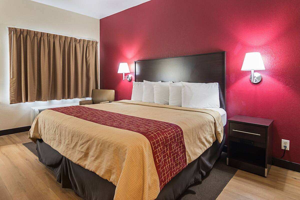 A hotel room with a large bed, two bedside lamps, a nightstand, and a chair.