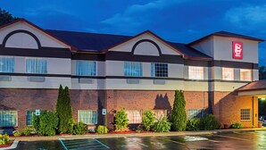 Um Red Roof Inn com fachada de tijolos, várias janelas e estacionamento.