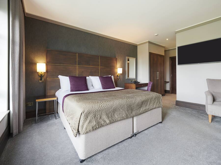 Ein modernes Hotelzimmer mit einem großen Bett, Nachttischen, einem Flachbildfernseher und einer Sitzecke mit einer Couch.