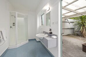 A modern bathroom with a glass-enclosed shower, a white sink, and a large mirror. - Fenton Court Motel (Rotorua)