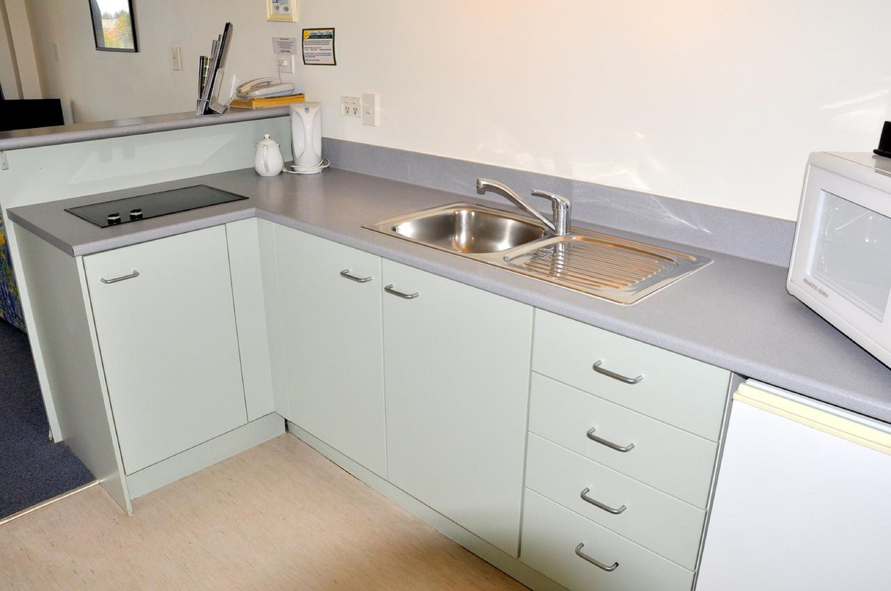 A compact kitchen with a sink, stove, and microwave.