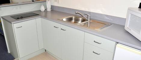 A compact kitchen with a sink, stove, and microwave.