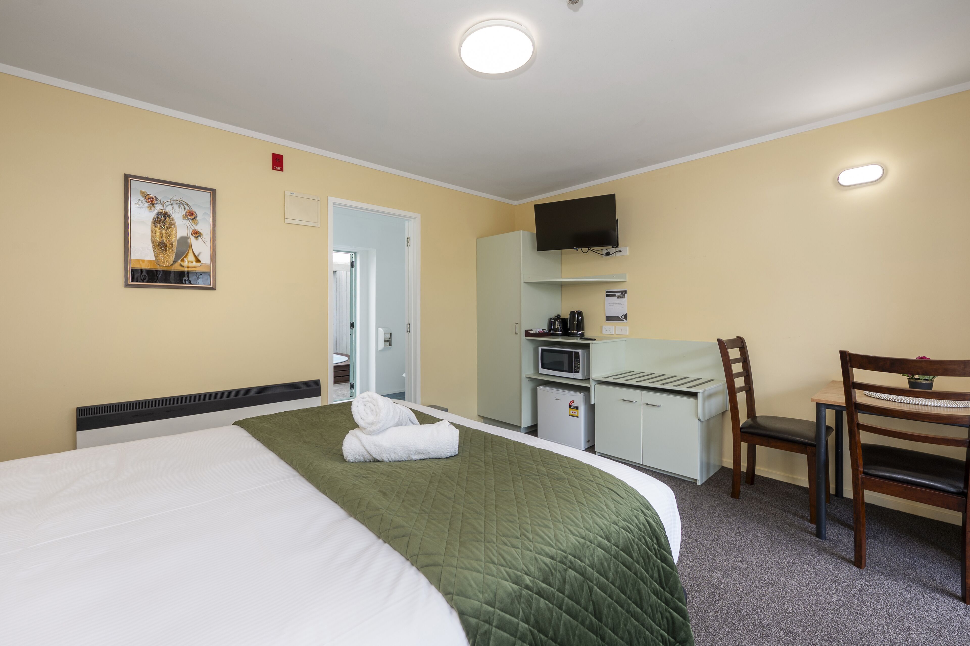A hotel room with a bed, a desk, a chair, a television, and a microwave.