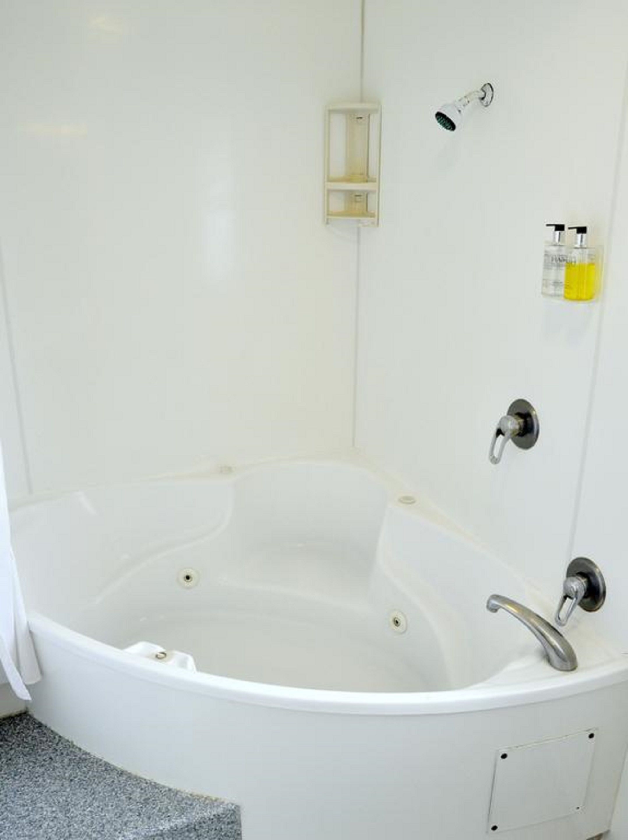 A white bathtub with a handheld showerhead and a handheld faucet.