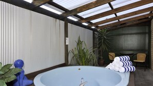 A spa area with a hot tub, seating, and plants. - Fenton Court Motel (Rotorua)