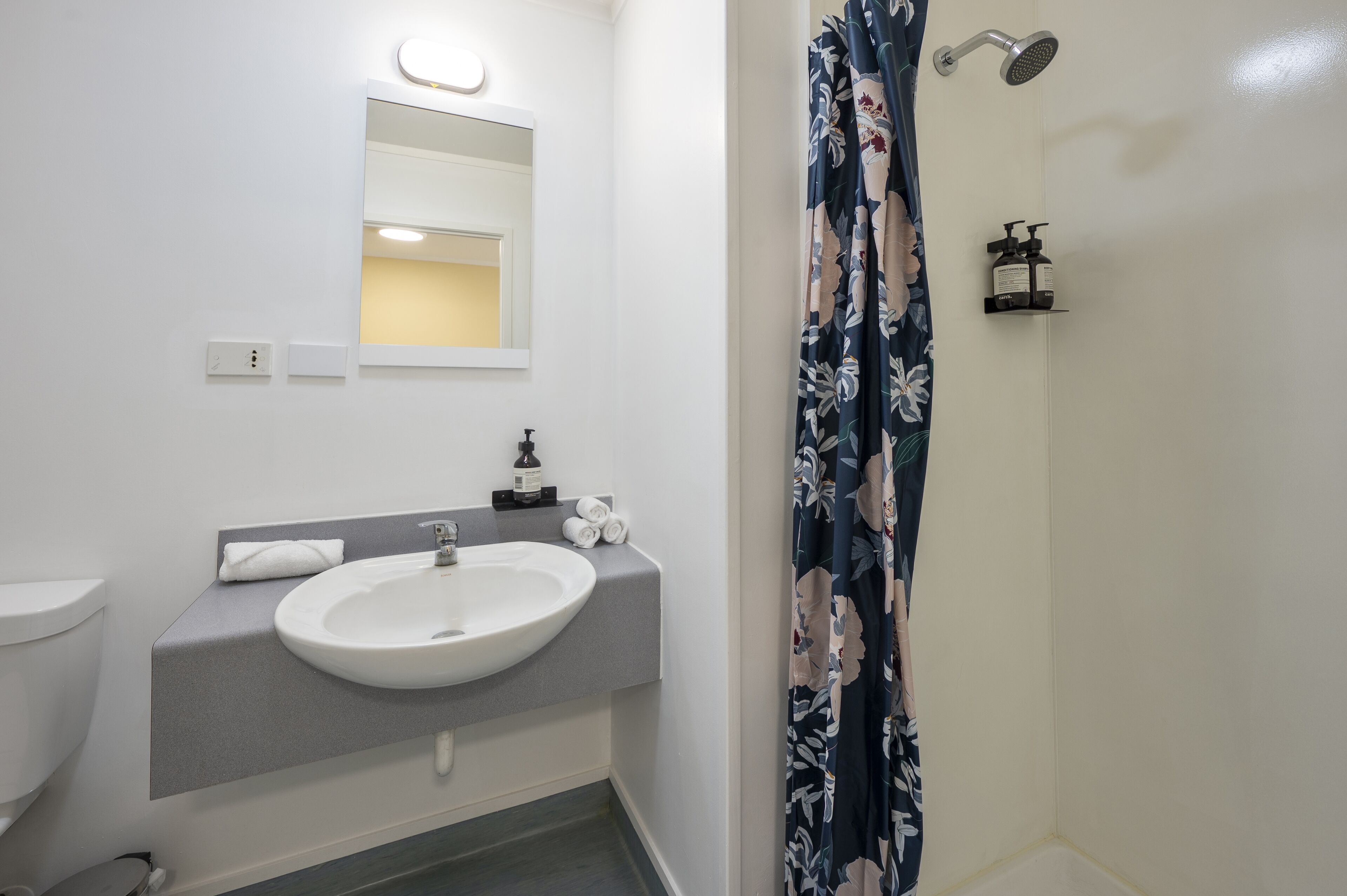 A bathroom with a white sink, mirror, and shower curtain.