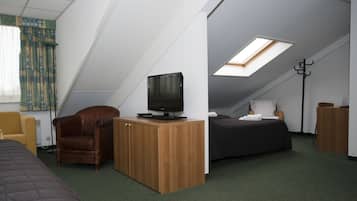 Habitación compacta con una cama, un escritorio con televisor, una silla y una cama con cubierta oscura.