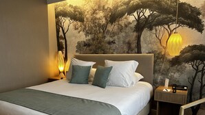 A neatly made bed with pillows, a nightstand with a lamp, and a wall mural of trees. - Best Western Plus Hotel Admiral (La Tour-de-Salvagny)