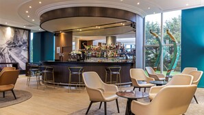 A modern bar area with a curved counter, bar stools, and a seating area with round tables and chairs. - Best Western Plus Hotel Admiral (La Tour-de-Salvagny)