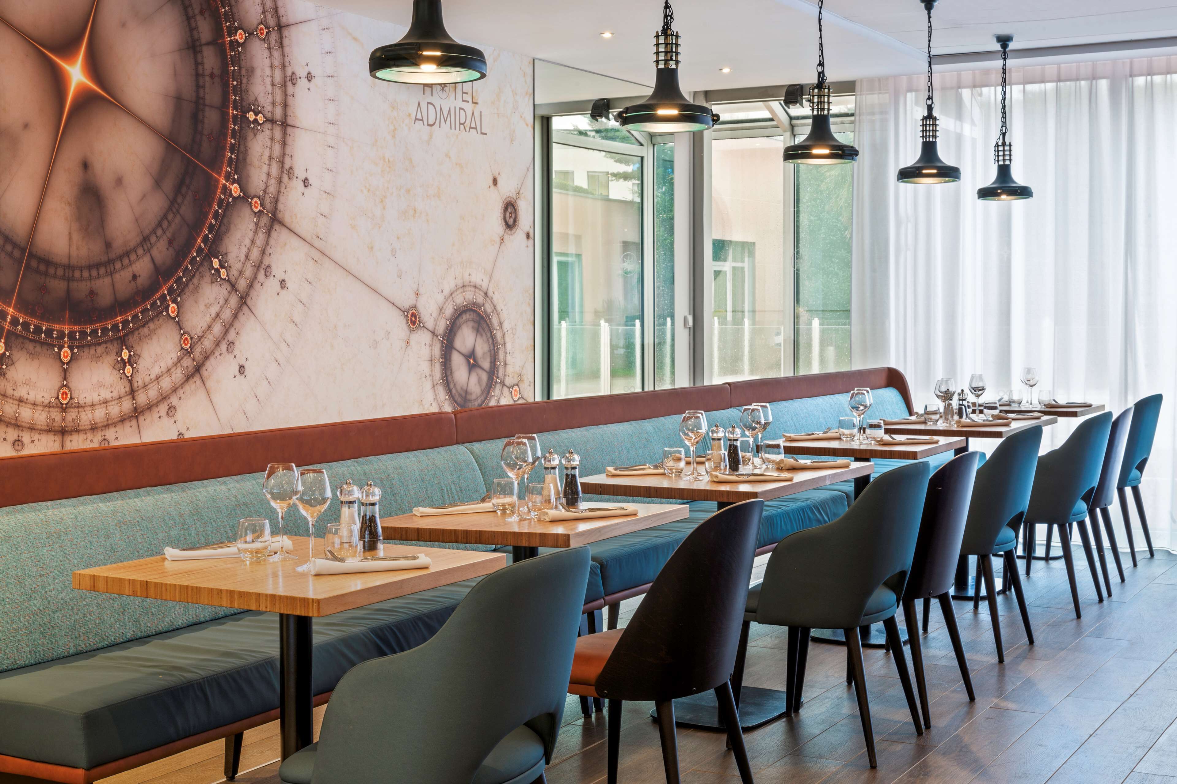 A restaurant with long wooden tables, blue cushioned booths, and black chairs.