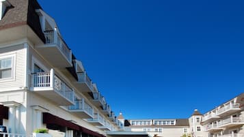 A multi-story hotel with balconies, a covered walkway, and a clear blue sky.