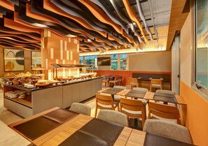 Un restaurant moderne avec un comptoir central, plusieurs tables et un design de plafond original.