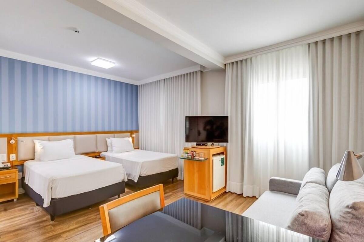 Ett hotellrum med två sängar, en TV, ett skrivbord och en soffa.