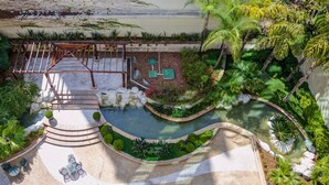 Un área exterior ajardinada con piscina, mobiliario y un pérgola.