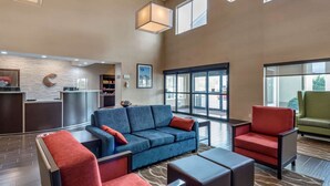 Un vestíbulo moderno con un sofá azul, sillones rojos y una mesa de recepción.