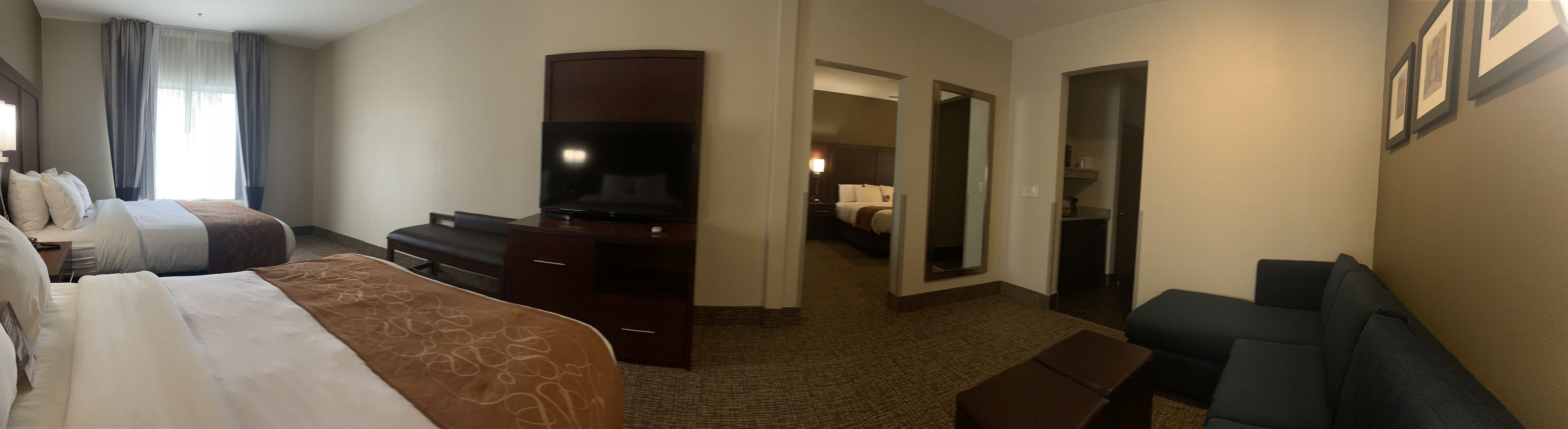 Camera d'albergo con due letti, una televisione, una scrivania e una sedia.
