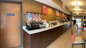 Un área de preparación de alimentos con una máquina de café, un expositor de comida y un letrero que indica la ubicación.