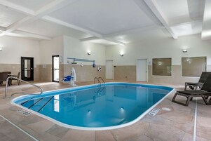 Una piscina interior con agua cristalina, un trampolín y tumbonas.